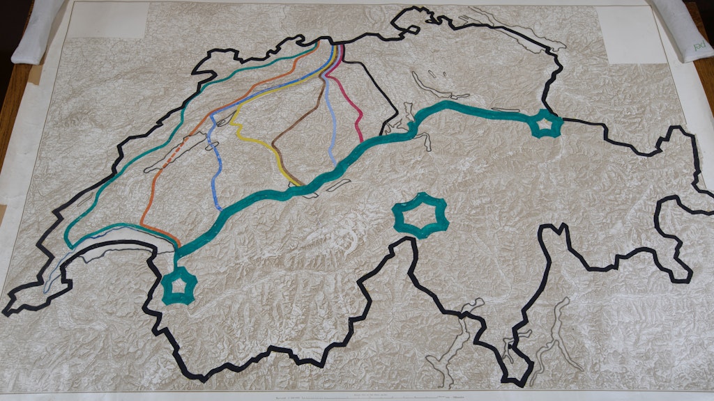 Carte en relief de la Suisse. La frontière nationale est marquée en noir. Une ligne turquoise grasse est tracée le long du flanc nord des Alpes. Elle marque la ligne de réduction. Les trois forteresses alpines de Saint-Maurice, du Gothard et de Sargans sont marquées. Le Plateau est traversé par plusieurs lignes de défense, indiquées par des couleurs différentes.