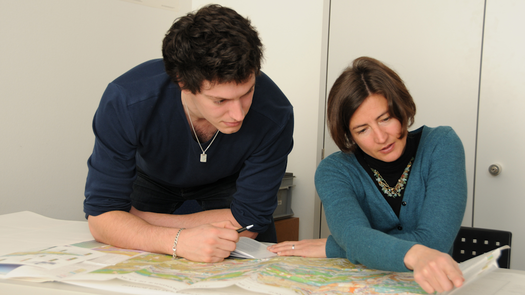 Stagista universitario con supervisore che osserva una carta geologica
