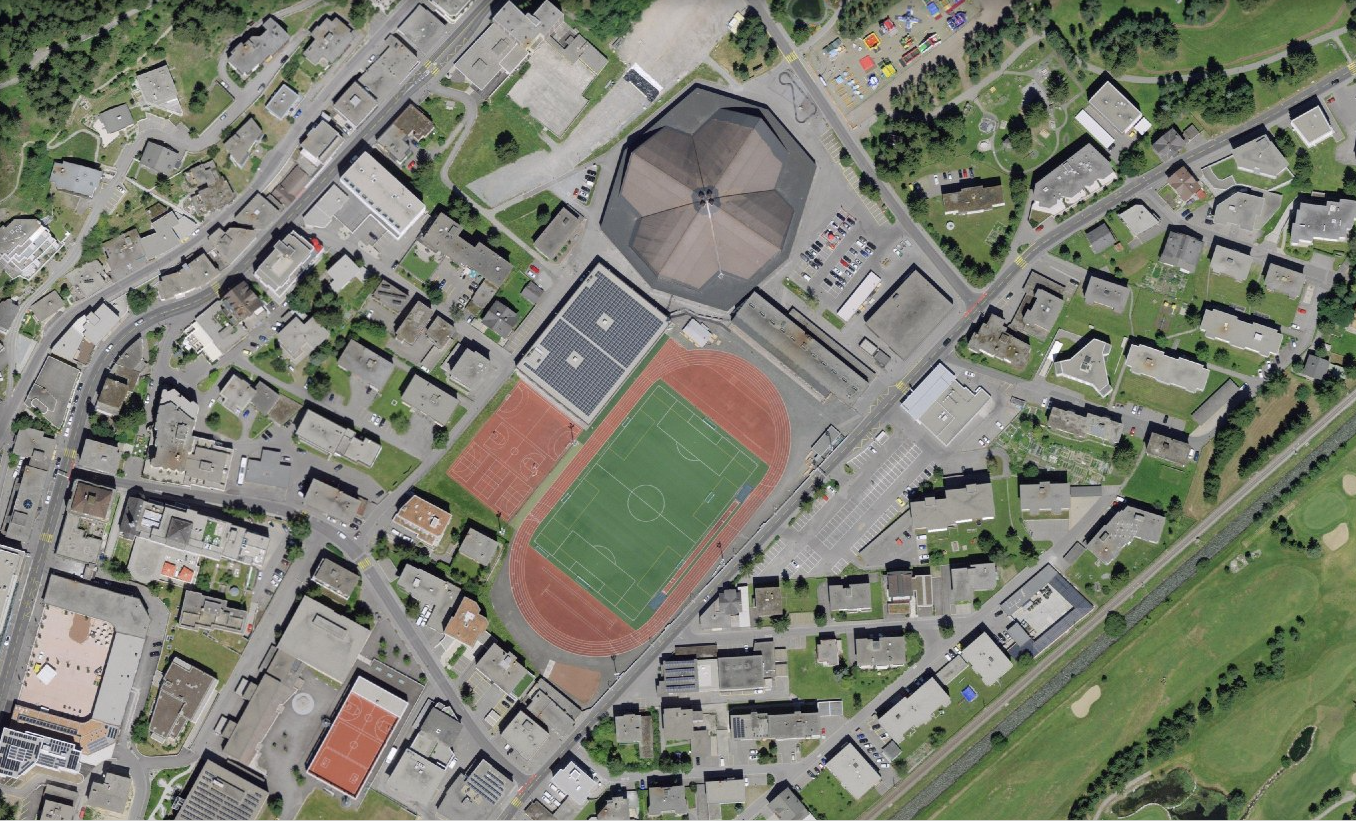 L'image montre une vue aérienne de Davos (GR) avec le centre sportif.