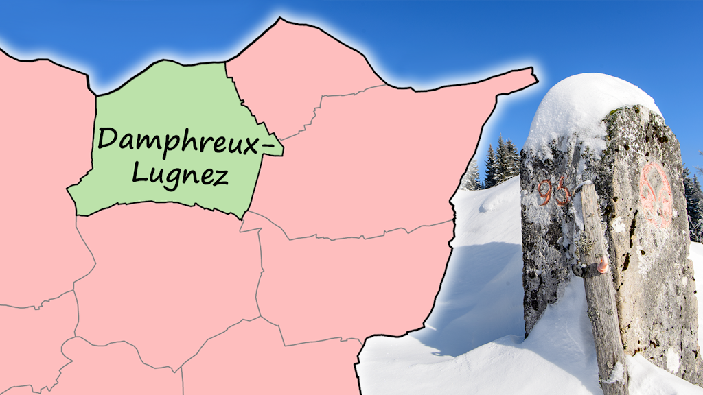 The picture shows a boundary stone in a snow-covered landscape on the right. On the left, the municipal boundaries in the northern part of the canton of Jura, in the French border region, with the municipality name 'Damphreux-Lugnez'. 