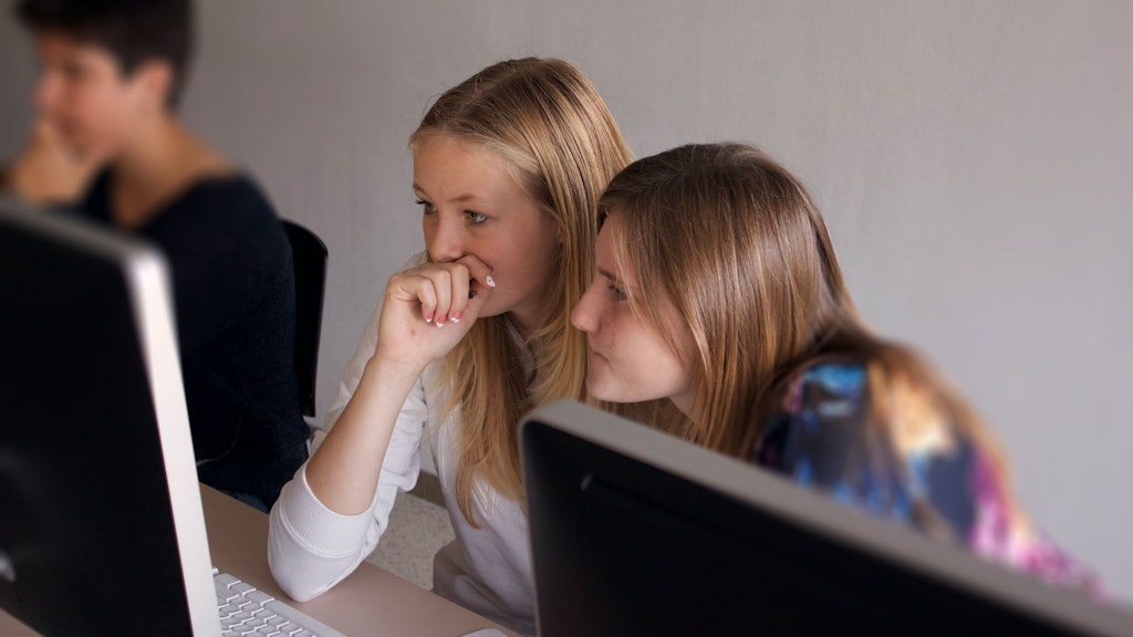 Due ragazze davanti a un computer, immagine aerea e carta