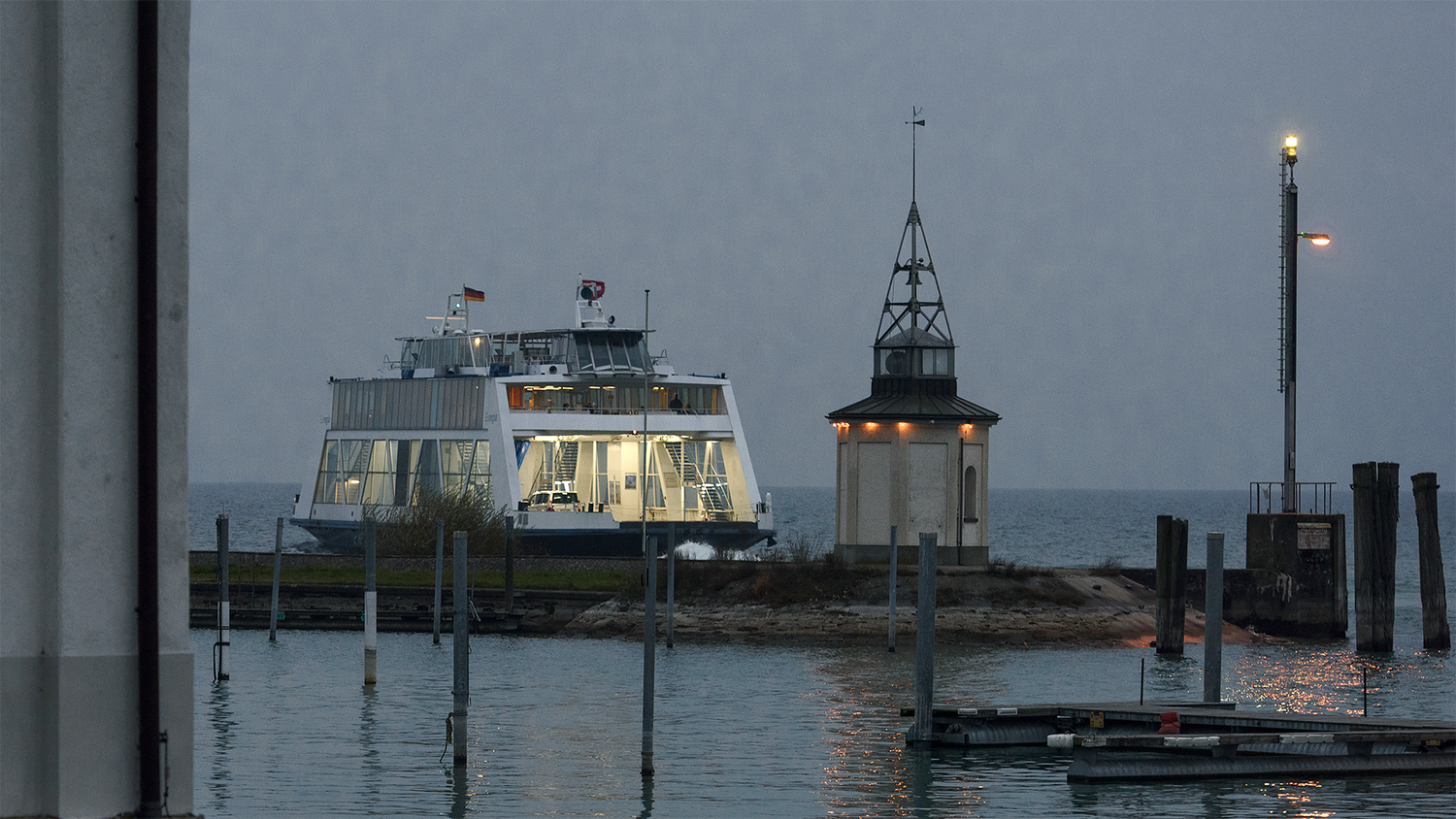 Hafen von Romanshorn in der Dämmerung, im Hintergrund eine Fähre, die Richtung Deutschland unterwegs ist.
