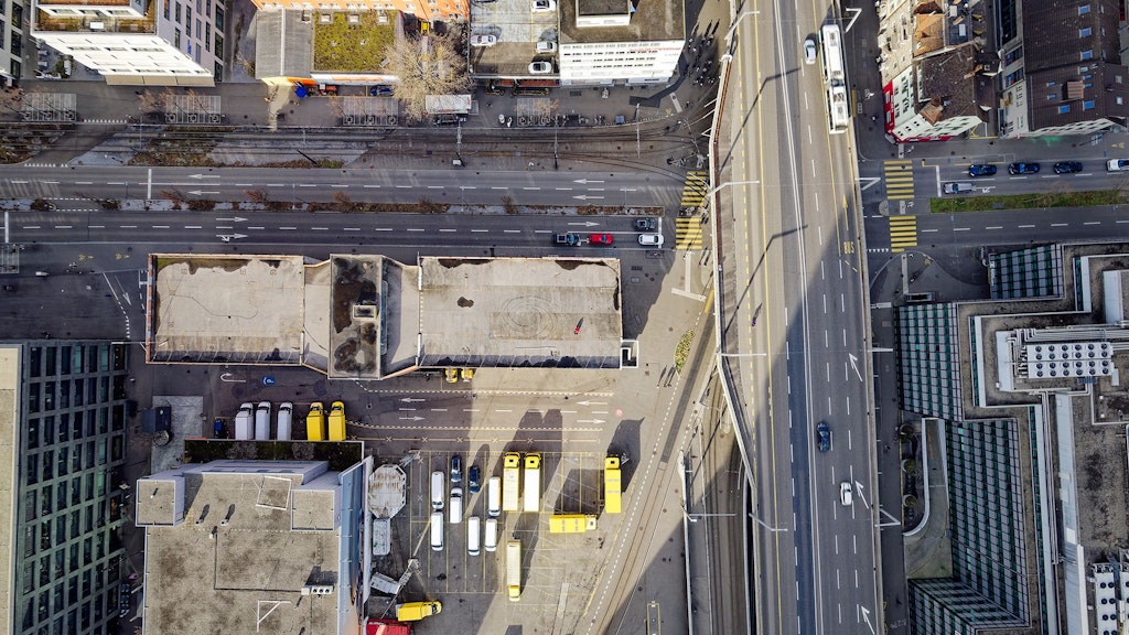 Vue aérienne des rues, des toits des bâtiments et du parking d'une entreprise de logistique dans une ville suisse.