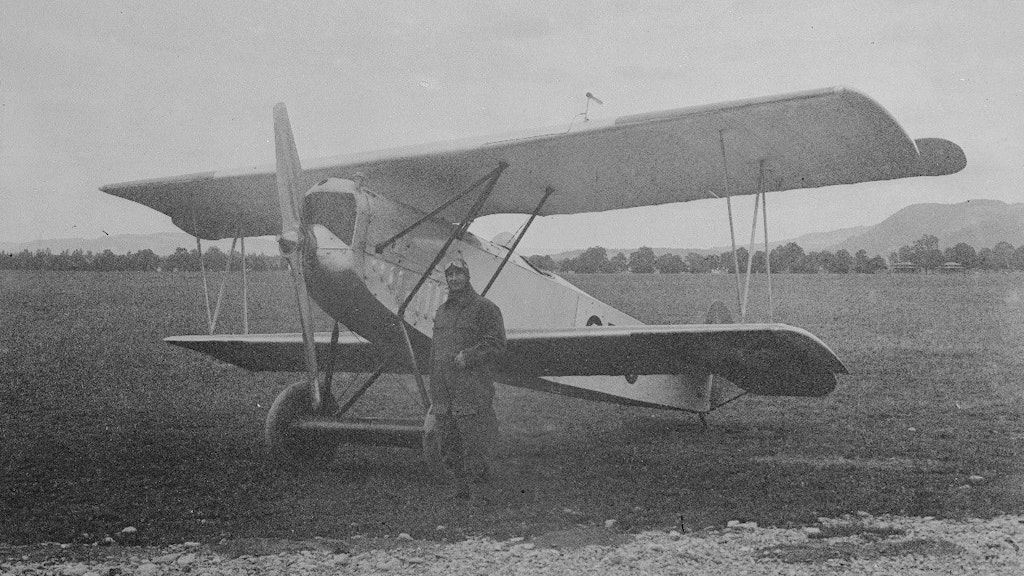Pilot vor Doppeldecker-Flugzeug auf dem Flugfeld. Historische Aufnahme.