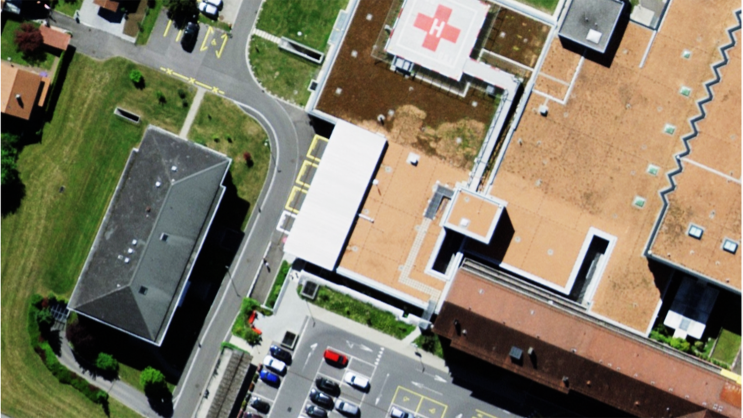 Spital von oben mit Parkplatz und Helikopter-Landeplatz