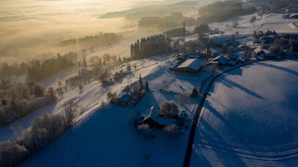 Winterlandschaft mit Sonnenaufgang im Nebel, in der Schweiz. Luftaufnahme