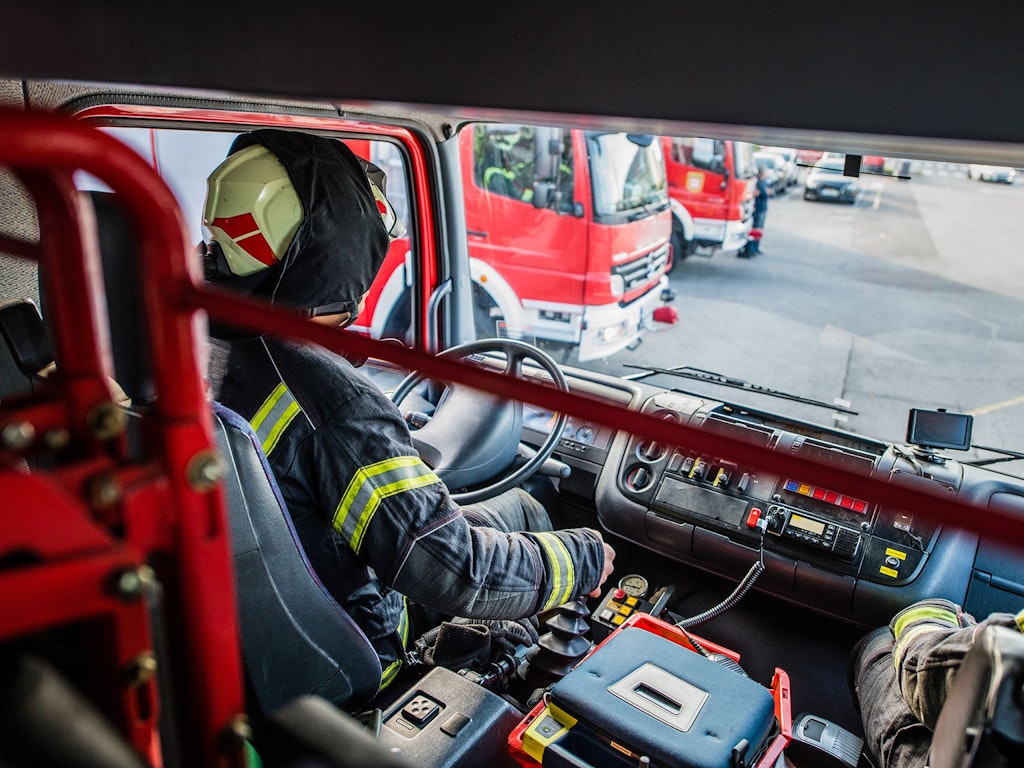 Innenansicht eines Feuerwehrautos über die Schulter des fahrenden Feuerwehrmanns.