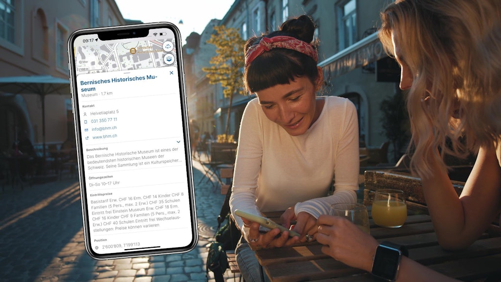 Screen einer Beschreibung eines POI mit zwei Frauen in Cafe im Hintergrund