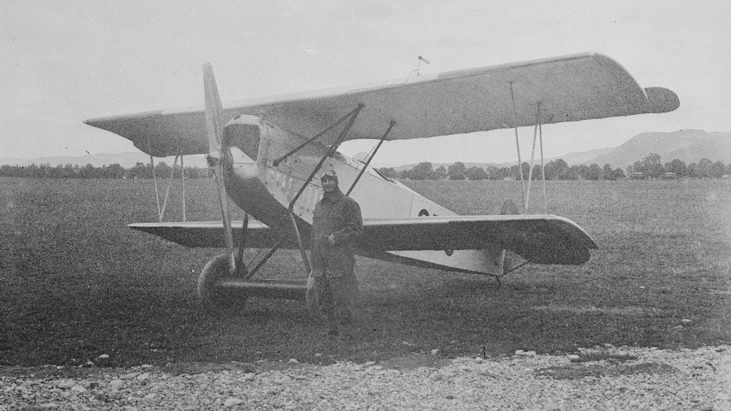 Pilot vor Doppeldecker-Flugzeug auf dem Flugfeld. Historische Aufnahme.