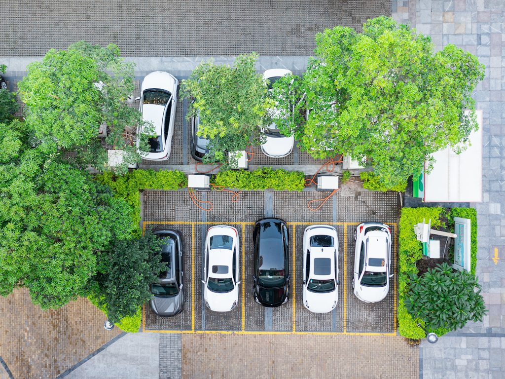 Luftaufnahme eines Parkplatzes mit Ladestation für Elektroautos.