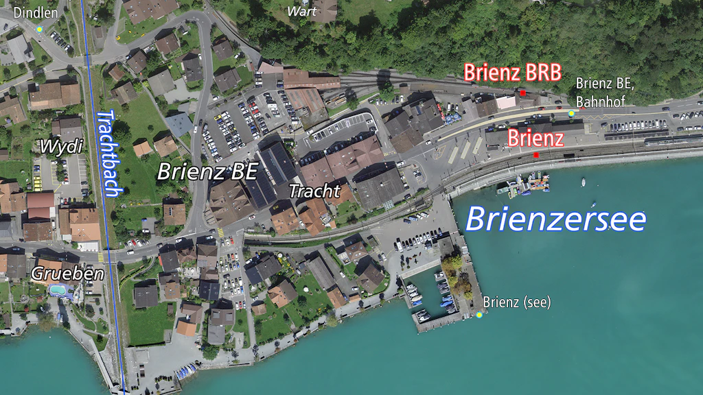 Das Bild zeigt eine Luftaufnahme von Brienz BE mit dem Dorf, dem Bahnhof und dem Brienzersee.