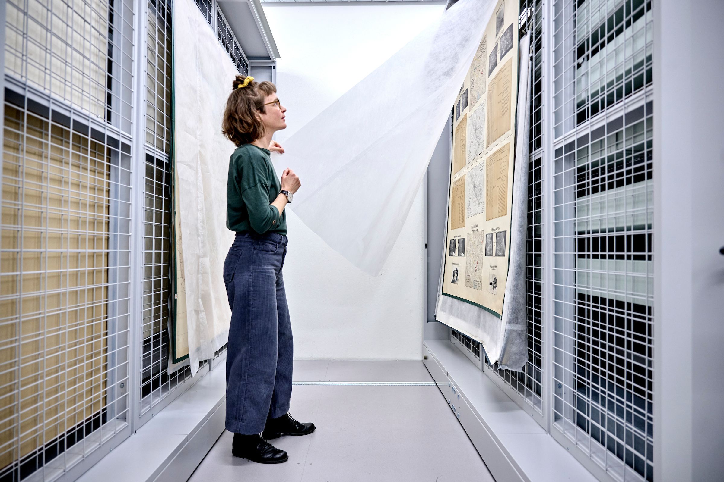 Lea Dauwalder schaut sich grossformatige Objekte an, die im Archivraum gelagert sind.