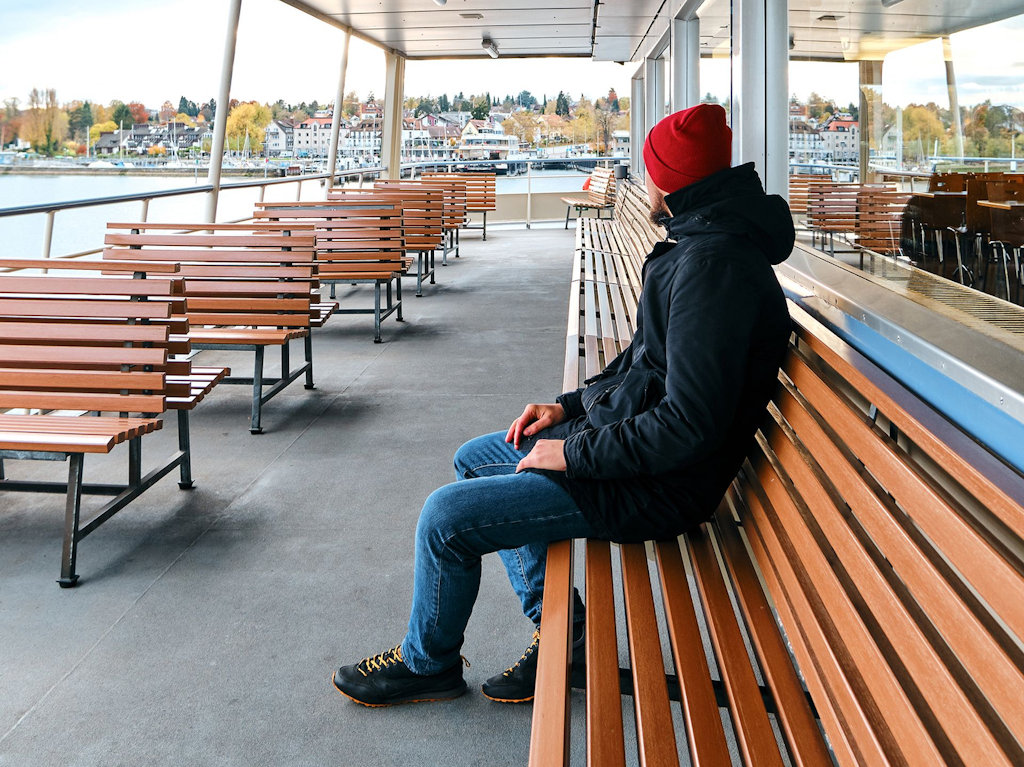 A man is sitting on the deck of a pleasure boat.
