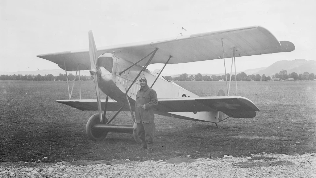 Pilot in front of a biplane on the airfield. Historical photograph.