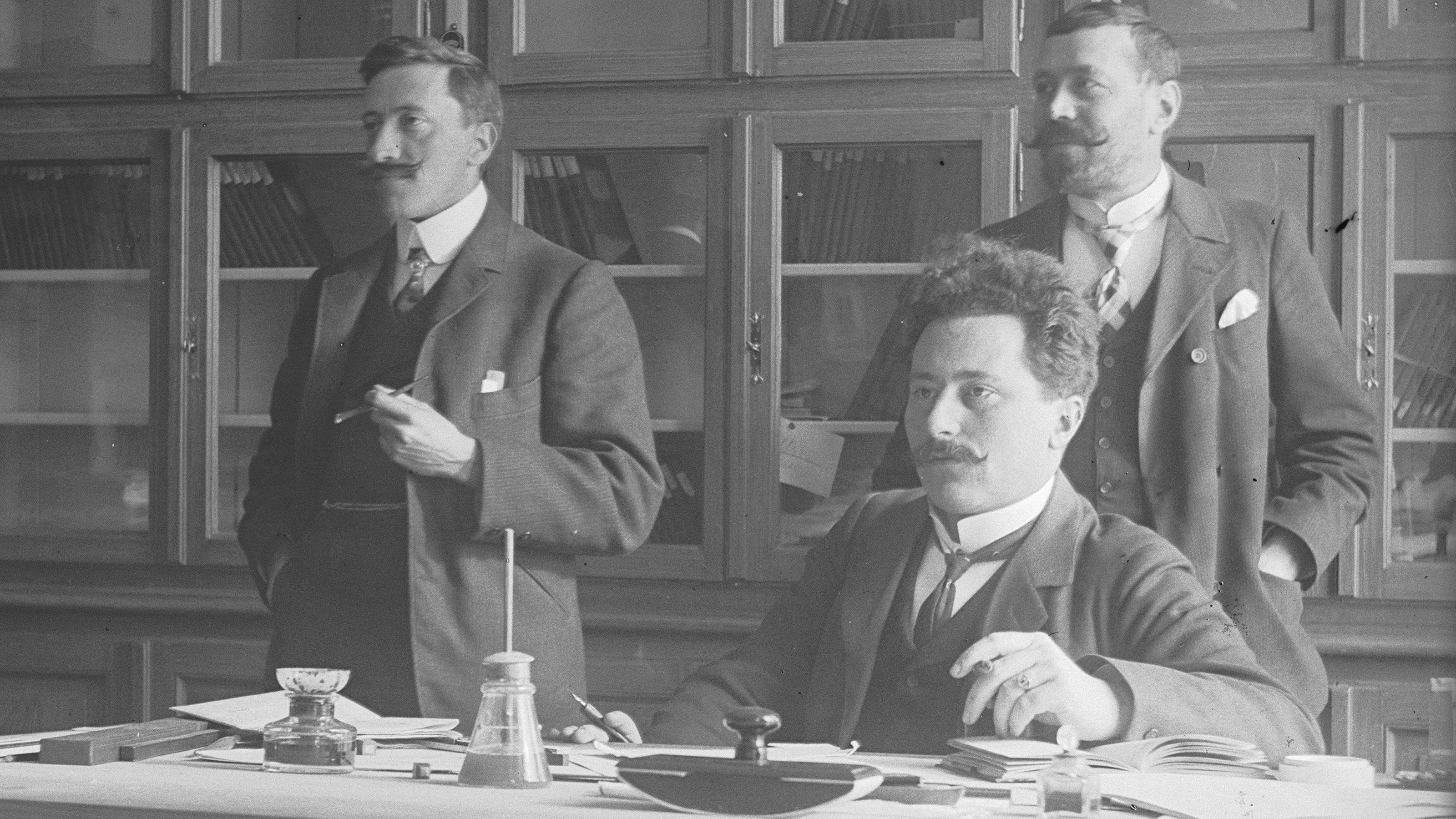 Simon Simonett avec deux collègues au bureau en 1912.
