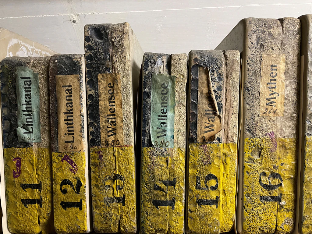 Six pierres lithographiques rangées les unes à côté des autres. Elles portent le nom de la feuille de carte correspondante. La photo montre à quel point ces pierres étaient larges et lourdes.