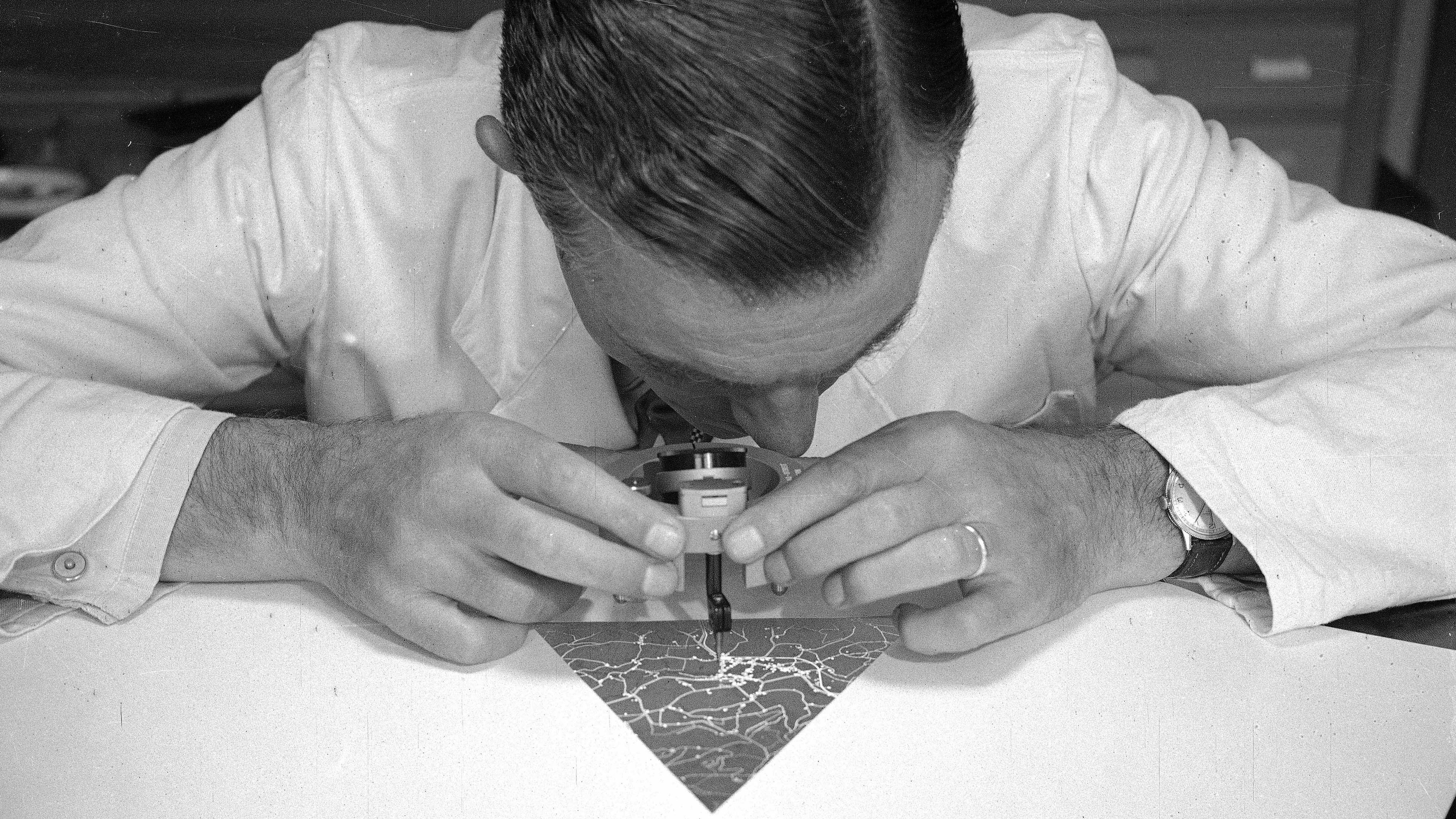 Un cartographe grave dans la couche de vernis sur verre, 1955.