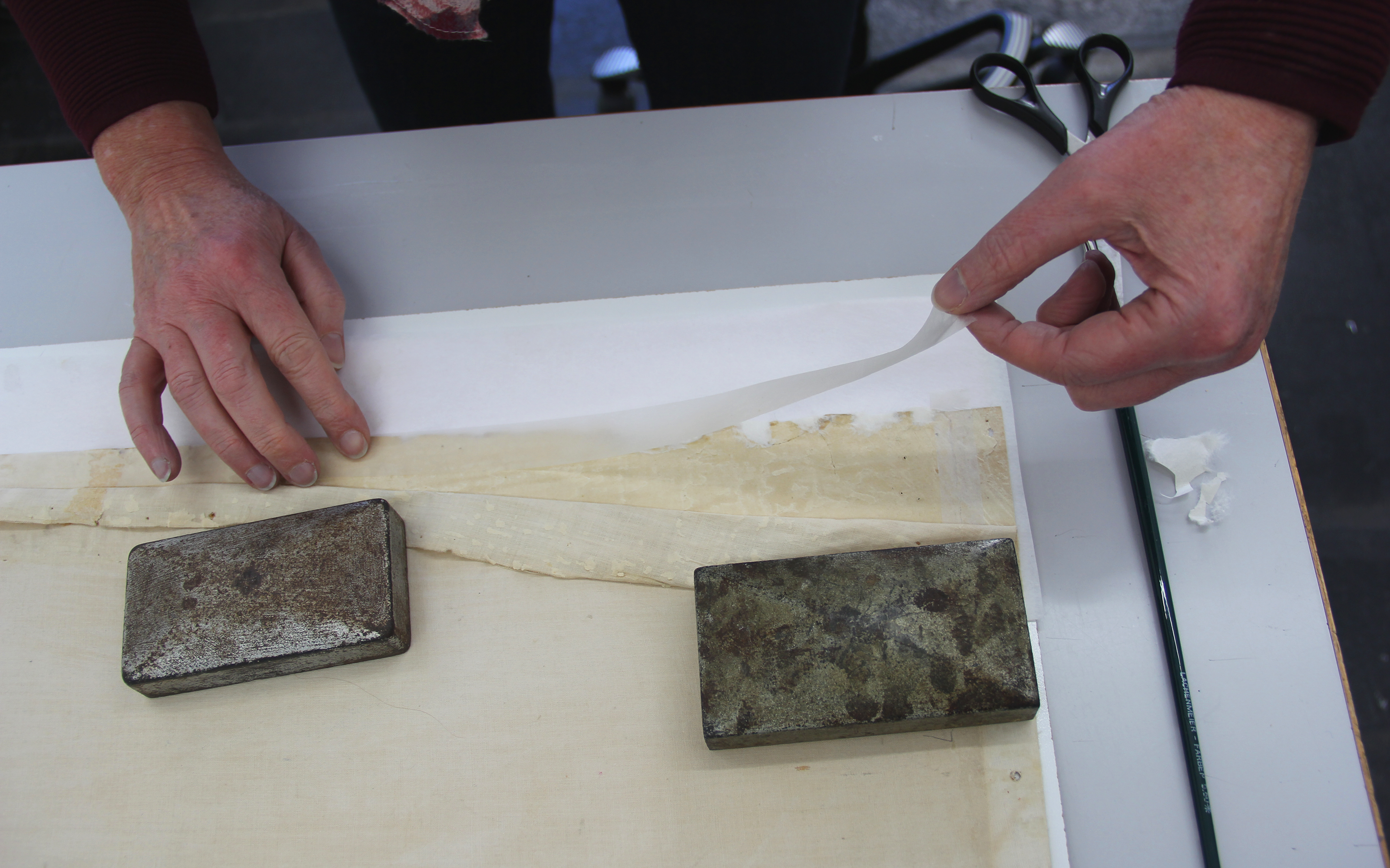 La pose de fines bandes de papier japonais permet de renforcer les bords de la carte et de fixer les déchirures du papier. La couche de lin d’origine est ensuite recollée par-dessus.