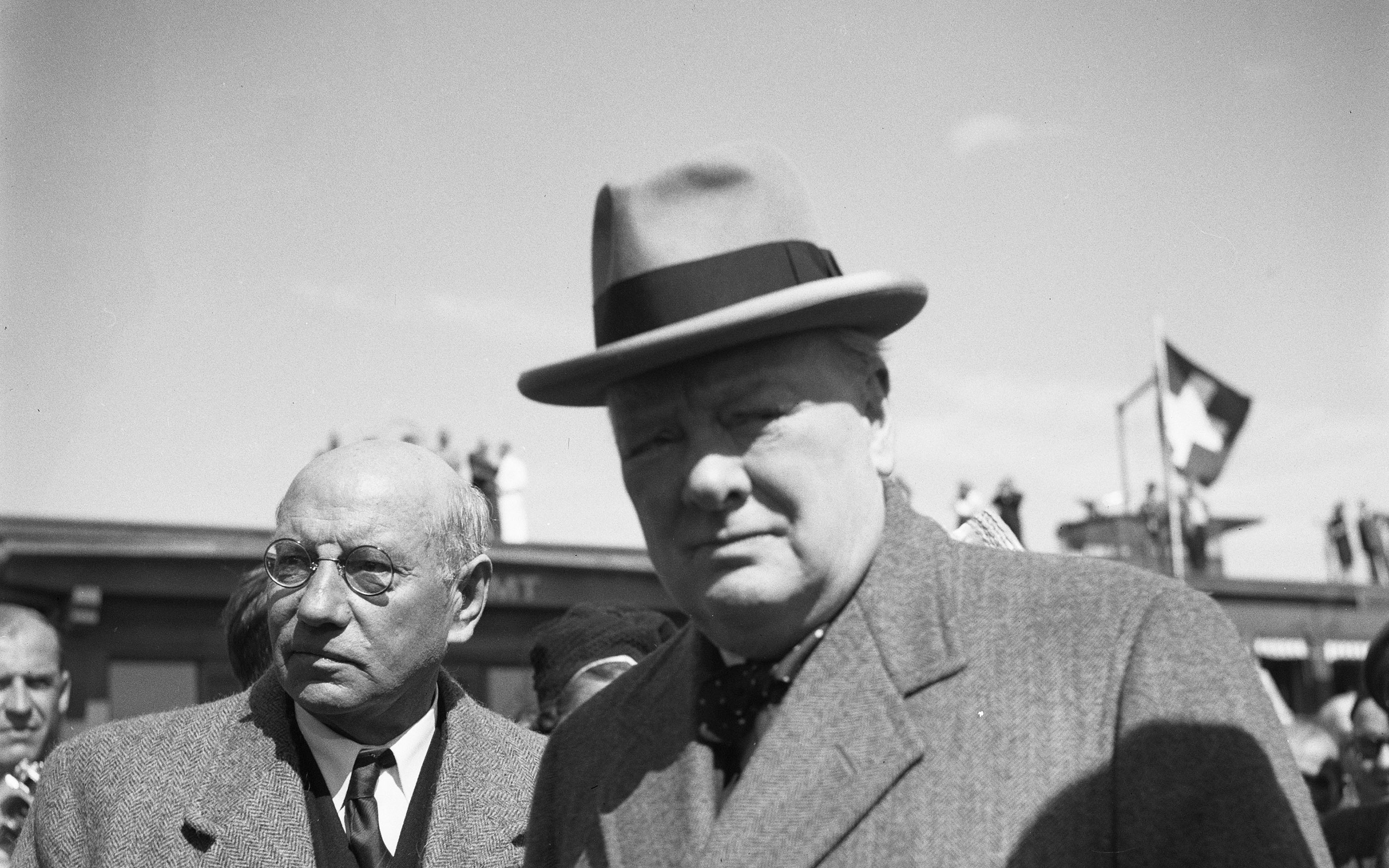 Winston Churchill à l'aéroport de Dübendorf. En arrière-plan, sur le toit de l'aéroport, on peut voir des badauds et un drapeau suisse.