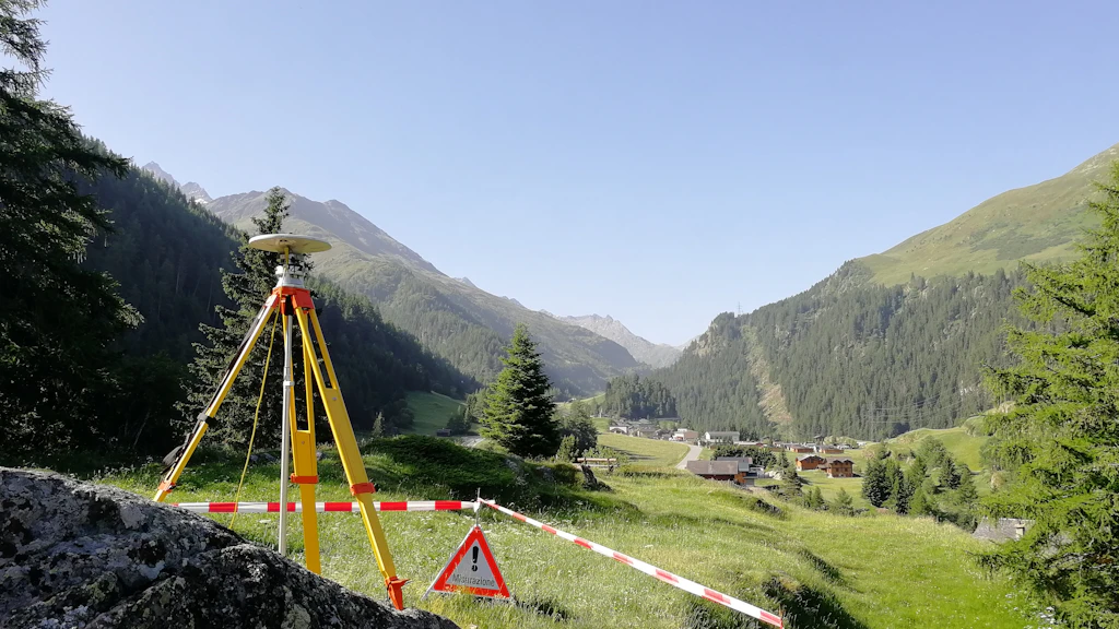 Ricevitore GNSS su treppiede in un'area delimitata in zona alpina.
