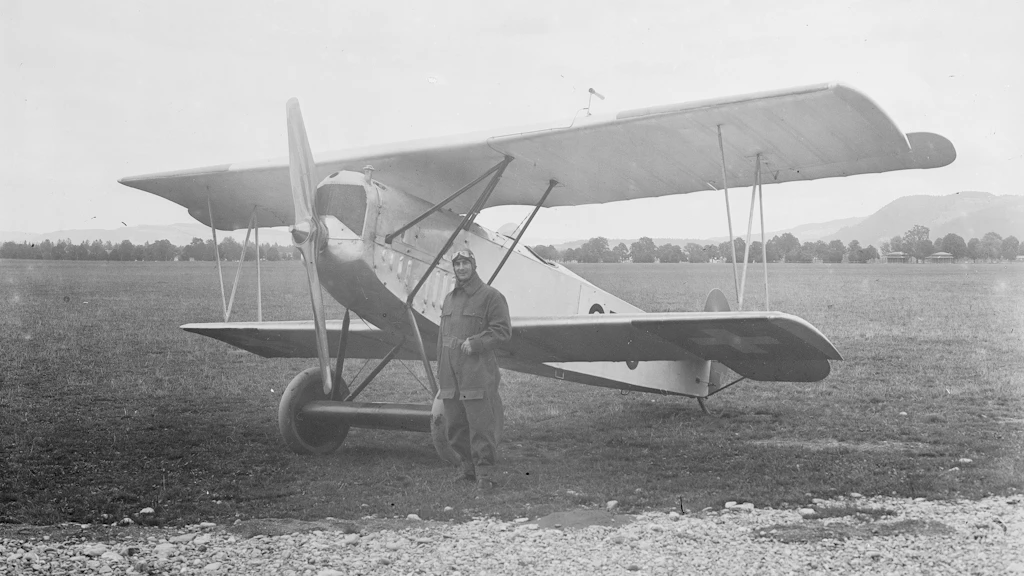 Pilota davanti a un biplano sull'aerodromo. Foto storica.